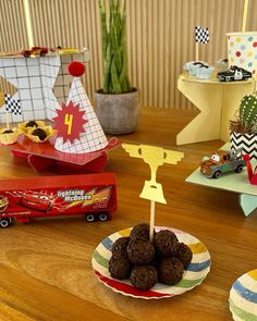 a table topped with paper plates filled with desserts and candies next to toy cars