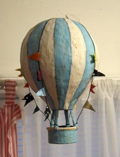 a blue and white hot air balloon with birds on it's side hanging from the ceiling