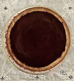 an overhead view of a chocolate pie on a tablecloth with white flowers and lace