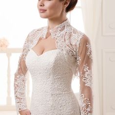 a woman in a white wedding dress with long sleeves and an open neckline is posing for the camera