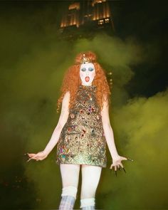 a woman with red hair and makeup on stage