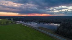 the sun is setting over a large body of water with trees in the foreground