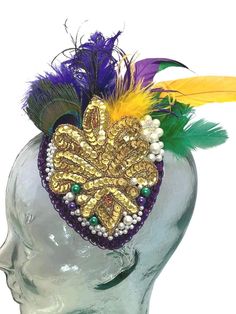 Mardi Gras Headpiece with purple, green, and gold assorted feathers. Main attraction to this piece is the beautiful gold sequin embellishment that lays in the center. A few added faux pearls and flower pearl accent attached. Perfect for Mardi Gras balls, parties, luncheons, brunches and of course anywhere in the French Quarter in New Orleans! This is all designed on a 4"x5" tear drop black  fascinator base. Mardi Gras Headpiece, Christmas Headpiece, New Orleans Christmas, Feather Headpiece, Black Fascinator, Sequin Embellishment, The French Quarter, Main Attraction, French Quarter