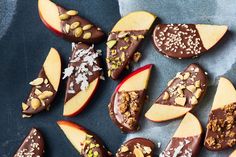 chocolate covered apples with nuts and almonds in them on a black surface next to a blue napkin