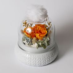 there is a glass dome with flowers in it and a white feather on the top