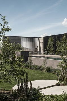 an outdoor swimming pool in the middle of a garden with trees and shrubs around it