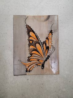 an orange and black butterfly painted on wood