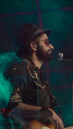 a man with a hat and glasses playing guitar