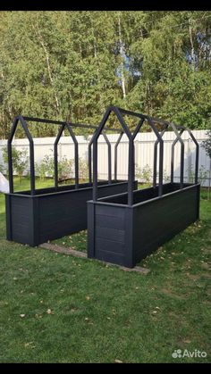 two large black planters sitting in the grass