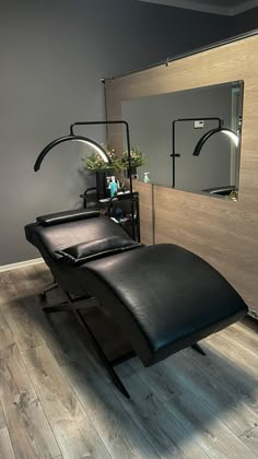 a black chair sitting in front of a mirror on top of a hard wood floor