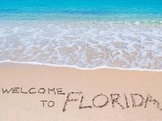 a welcome to florida written in the sand at the beach with starfish and seashells