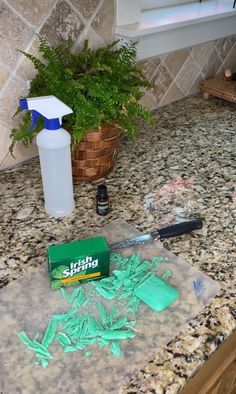 a counter top with green stuff on it and a bottle of cleaner next to it