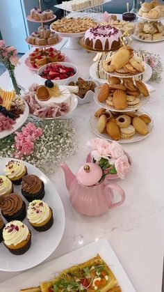 a table topped with lots of different types of cakes and cupcakes on top of plates