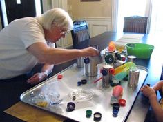 an older woman and two young boys playing a game on a metal tray at a table