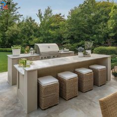 an outdoor kitchen with wicker stools next to it and grill in the background