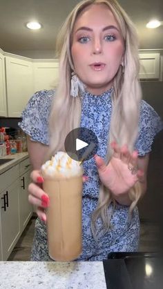 a woman holding up a drink with whipped cream in it