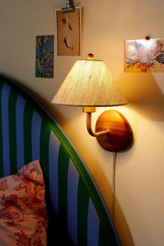 a lamp that is on the side of a wall next to a bed with pillows