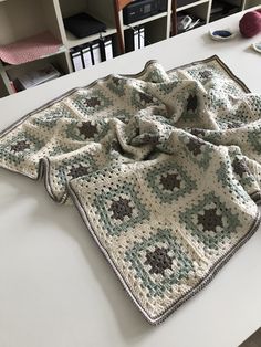 a crocheted blanket sitting on top of a table next to a book shelf