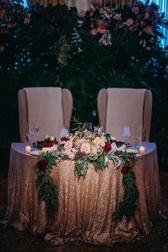 the table is set for two with candles and flowers on it in front of some chairs