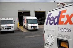 two fedex trucks are parked in front of a building with an exit sign on it