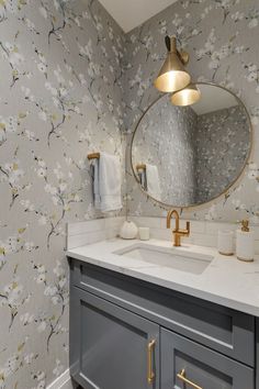 a bathroom sink with a mirror above it and wallpaper on the walls behind it