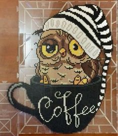 an owl in a knitted hat is sitting on top of a coffee cup with the word coffee