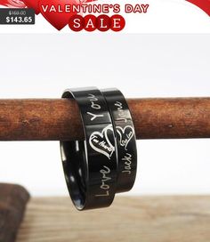 two black rings with hearts on them sitting on top of a wooden stick