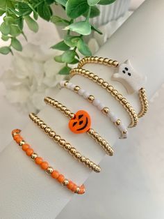 the bracelets are decorated with gold beads and orange bead accents, including a pumpkin