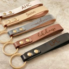 four leather keychains with engraved names on them, all in different colors and sizes