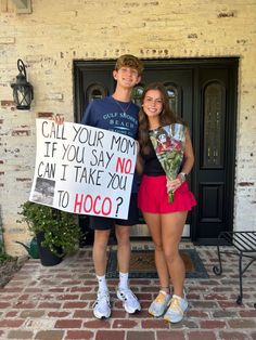 a man and woman standing in front of a door holding a sign that says, call your mom if you say no can i take you to hoo?