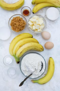 bananas, eggs and other ingredients are laid out on a white tablecloth to make banana bread