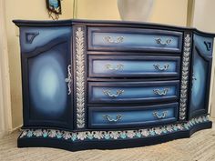 a blue dresser with ornate designs painted on it