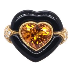 A heart within the heart! Absolutely stunning heart-shaped, orange sapphire surrounded by migrain and then custom cut onyx in an 18k yellow gold setting. This custom setting is specifically tailored for the brilliant sapphire, with diamonds on the profile and down the shank. The orange sapphire weights 4.7 carats total weight while the round brilliant diamonds amount to 1.13 carats in setting. Ring Size: 6.5 & can be sized One of a kind, cannot be replicated. Heart Cocktail, Orange Sapphire, Yellow Gold Setting, Jewelry Rings Engagement, Cocktail Ring, Cocktail Rings, A Heart, Onyx, Heart Shapes