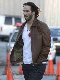 a man with dreadlocks is walking down the street in front of traffic cones