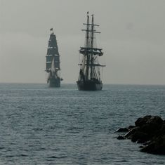 two ships are sailing in the ocean on a foggy day and one is off to the side