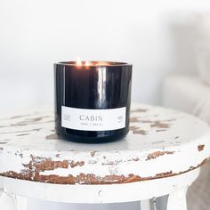 a black candle sitting on top of a white table next to a chair in a room