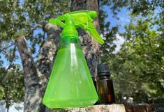 a green spray bottle sitting on top of a rock next to an empty glass bottle