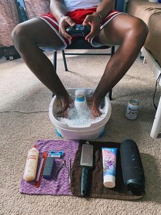 a man sitting in a chair on the floor with his feet in an ice bucket