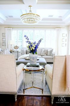 a living room with couches, chairs and a chandelier in the corner