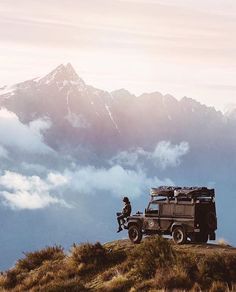 a man sitting on top of a hill next to a truck