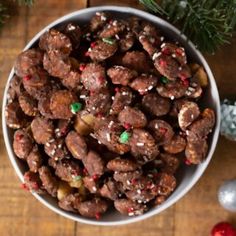 a white bowl filled with chocolate covered nuts and sprinkles on top of a wooden table