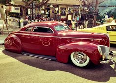 an old red car parked in front of a building