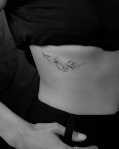 a black and white photo of a woman's stomach with a flower tattoo on it