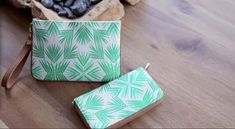 two small green and white bags sitting on top of a wooden floor next to rocks