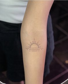 a woman's arm with a small sun tattoo on the left side of her arm