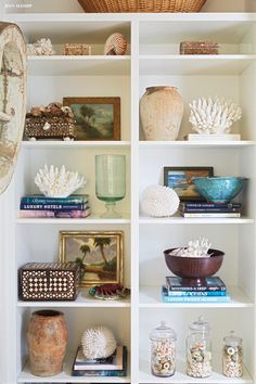 a white book shelf filled with lots of books and vases on top of it