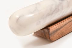 a white marble object sitting on top of a wooden stand in front of a white background