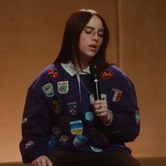 a woman sitting down with a microphone in her hand