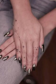 a woman's hands with silver nail polishes and stars on her nails, sitting on a couch