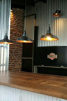 three lights hanging from the ceiling above a counter in a bar with brick walls and barstools